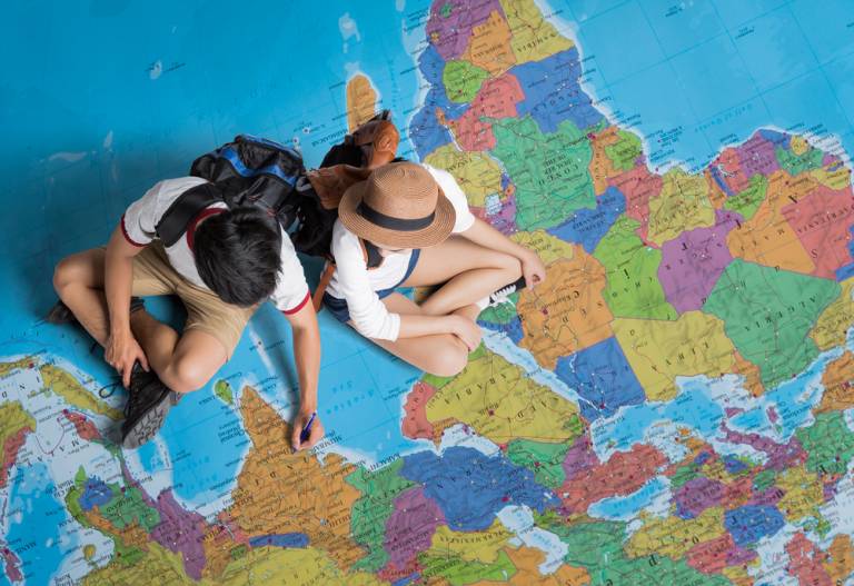 Two people sat on the map of the world