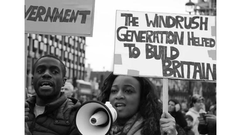 image of a person holding a placard with wording about the Windrush scandal