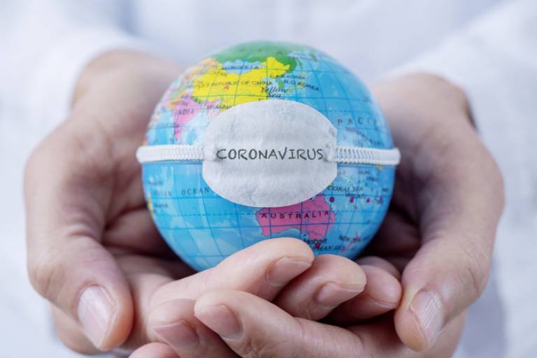 A pair of hands holding a globe with the word coronavirus written on it