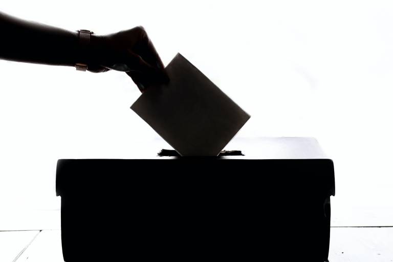 Person casting their ballot in a ballot box