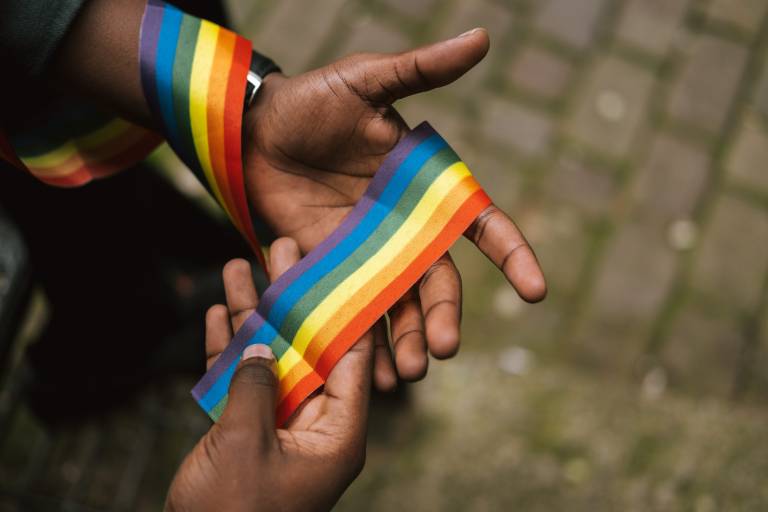 Hands holding a rainbow ribbon