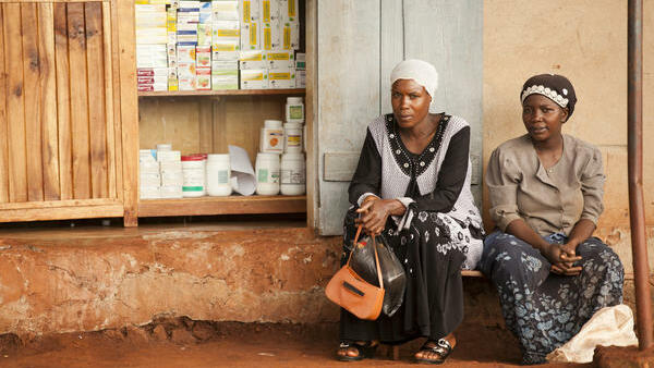 Two women sat next to a pharmacy