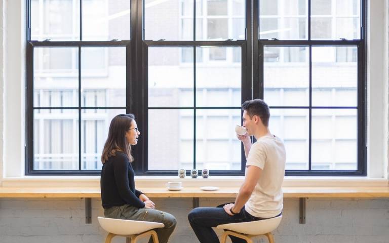 a young woman and man talking to one another over a cup of tea