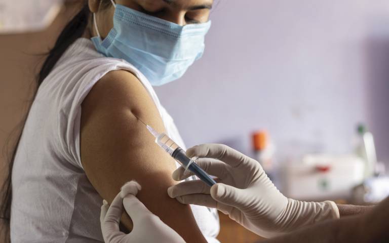 vaccine for covid-19 is being given to an Indian woman wearing face mask