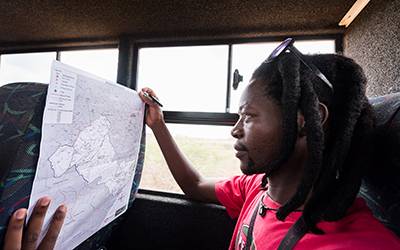Jabulani Sibiya studies a map of households that make up the Africa Health Research Institute’s population research area. Image: Ben Gilbert, Wellcome…