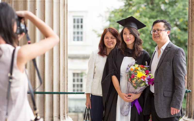 UCL graduate with family, flowers and photographer