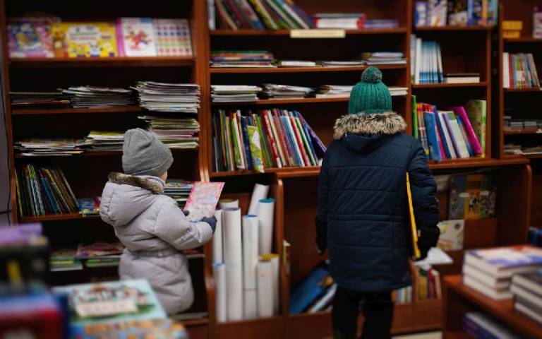 Children in coats reading in Library 