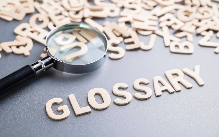 Word glossary spelt in wooden letters with magnifying glass 