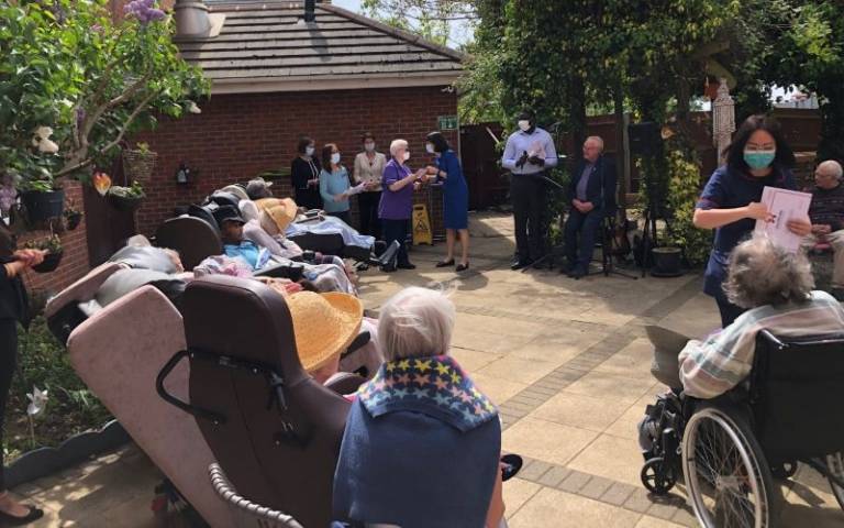 Care home residents sit in the garden outside listening to a talk given by covid 19 VIVALDI researchers