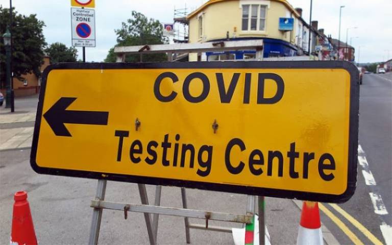 Yellow traffic sign directing to COVID testing centre