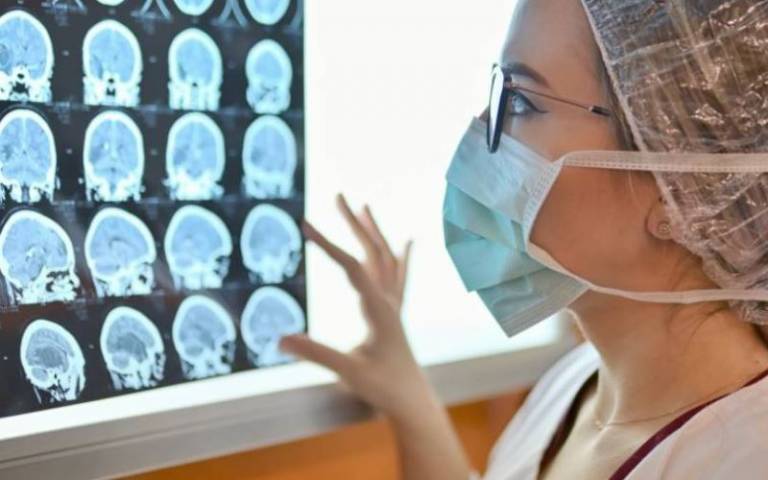 Researcher wearing mask looks at brain scans