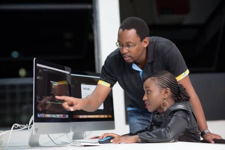 An adult man shows a young woman something on a computer screen