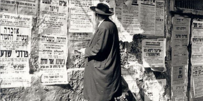 black and white photo of Ashkenazi Man looking at posters on a wall