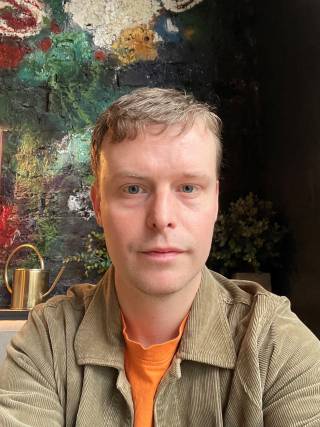 a man with short blonde hair looks at the camera