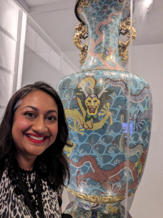 Dr Sushma Jansari smiling in front of Asian Art (Vase)