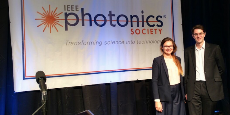 Dr Lavery and Balakier in front of the IEEE Photonics Society banner