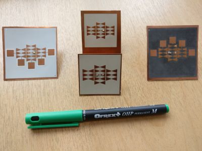 Several photographs of antenna designs, next to a pen for scale, the antenna arrays are approximately 1/4 the length of the pen. 