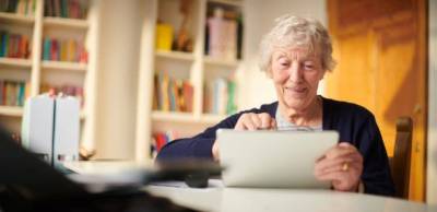 An elderly woman at home using the Gotcha! app on her digital tablet 