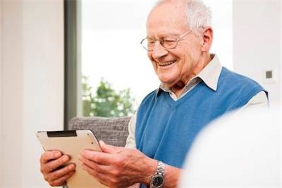 An elderly man at home using the Gotcha! app on his digital tablet. 