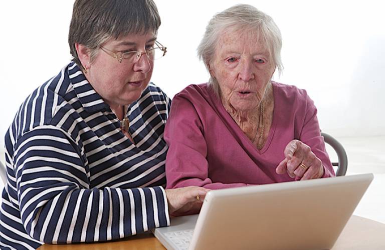 Elderly woman getting help with a computer