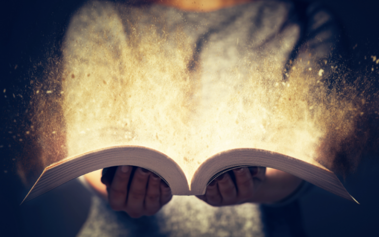Woman holding an open book bursting with light