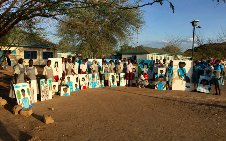 Group of African school children showing their paintings outside their school