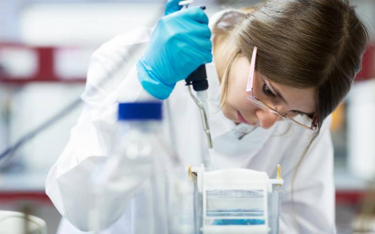 Image shows female student using a pipette in a laboratory