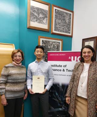 Francis Lu, a Chinese student, stands between two female IFT professors. He is holding a certificate and smiling at the camera