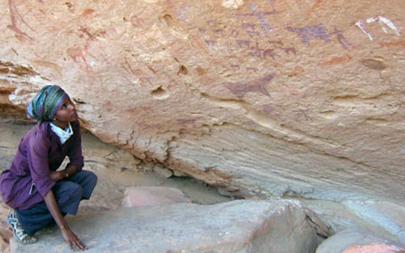 Woman looking at cave paintings in Africa, research in Africa