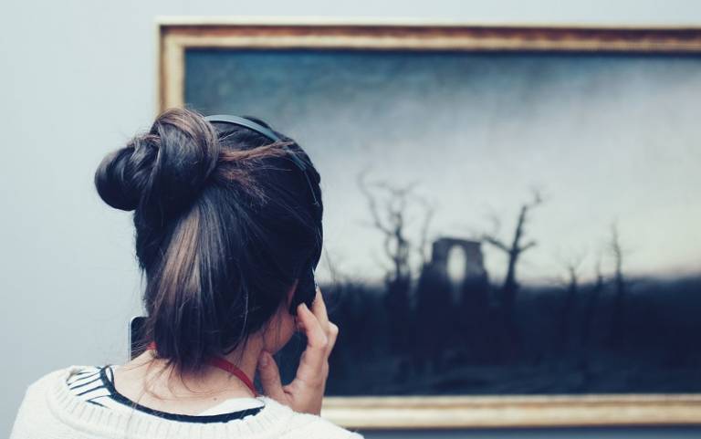 woman using audio guide in gallery, photo by Mike Kotsch on Unsplash