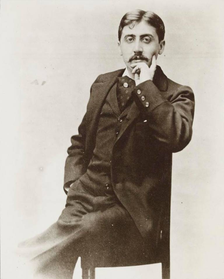 A black and white photograph of Marcel Proust. he is looking directly into the camera, his chin rests on his left hand