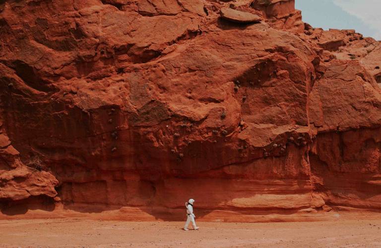 person in spacesuit in desert landscape
