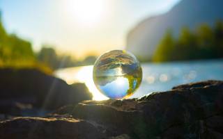 glass ball reflecting a river and mountains, Photo by Alin Andersen on Unsplash