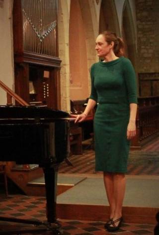 Annika Lindskog stands beside a piano