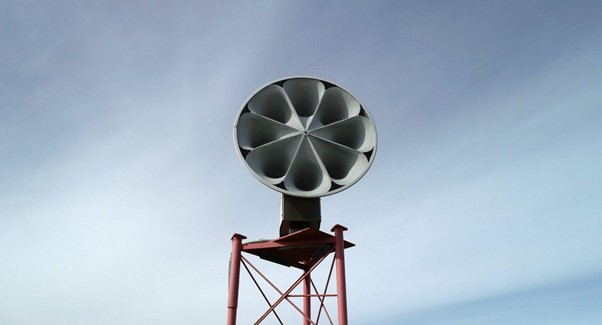 An image of a siren sitting atop a stand against the background of the sky