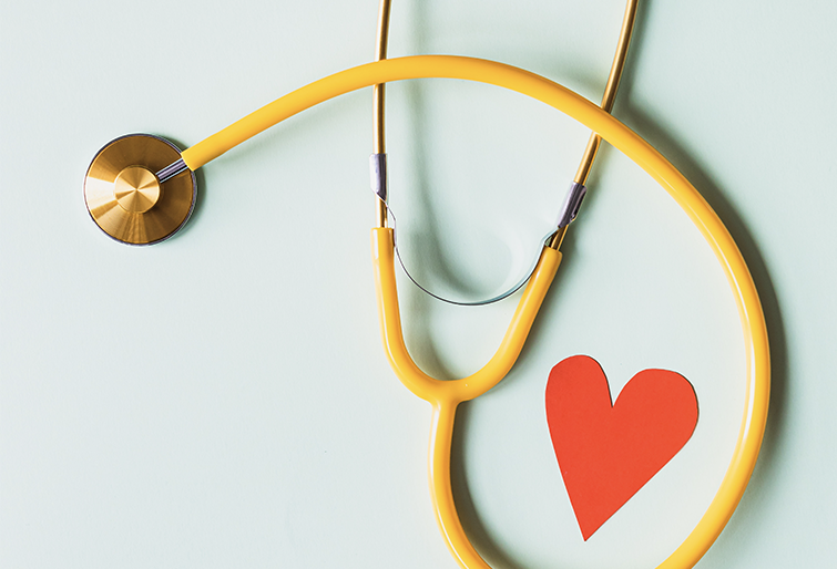 a yellow stethoscope on a table with a heart drawn by it
