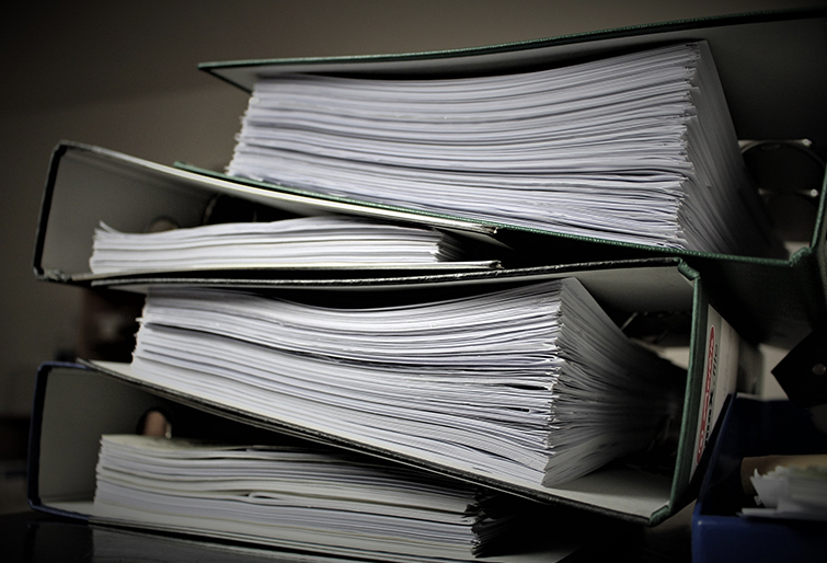 a pile of ring binders filled with paper stacked on top of one another