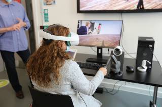 wide area haptics - a women uses a VR headset and haptics to collaborate on a simulated task