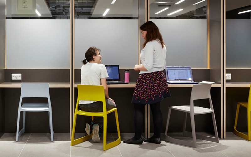 Two people chatting in a IOE workspace. IOE.