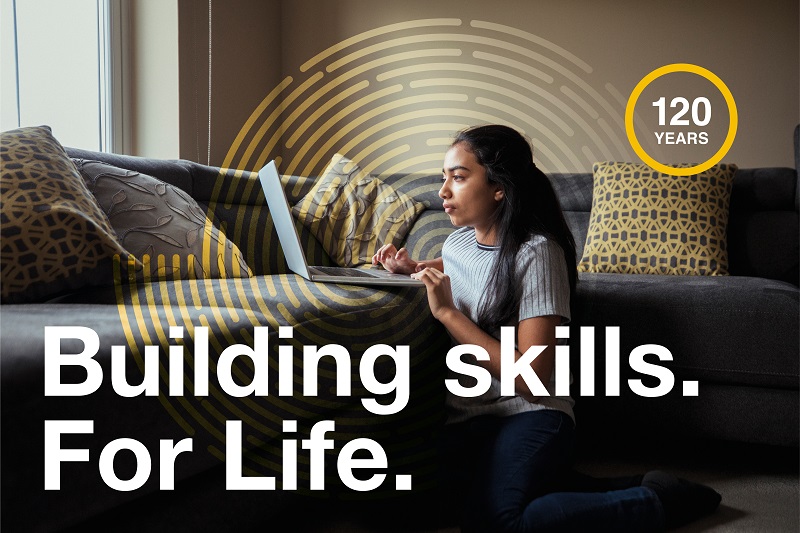 Teenage girl using laptop with white text ‘Building Skills. For Life.’