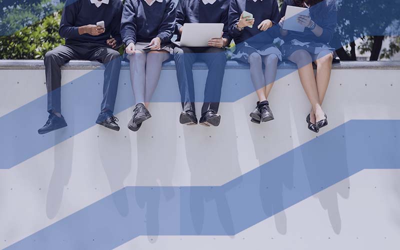 School students sitting on top of a wall