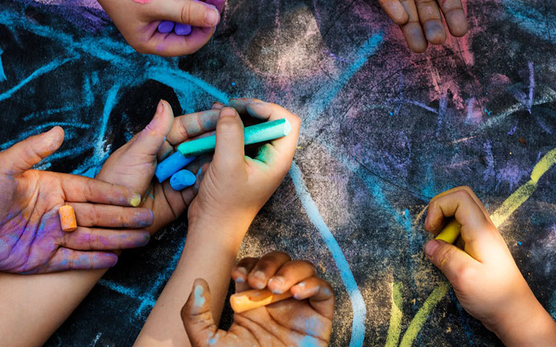 Children's hands holding coloured chalk