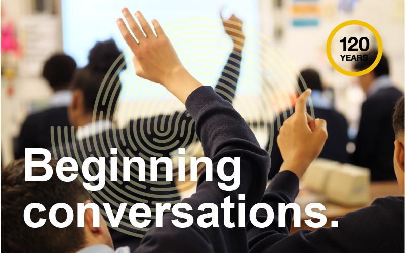 Secondary school pupils raising their hands in class with white text 'Beginning conversations.'