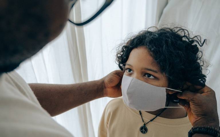 Man helping child put on face mask