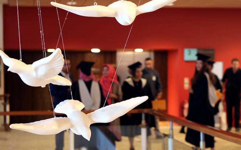 Hanging sculptures of birds in flight in front of graduating students