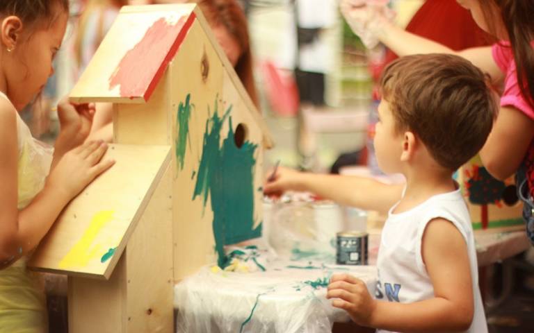 Small boy painting in nursery