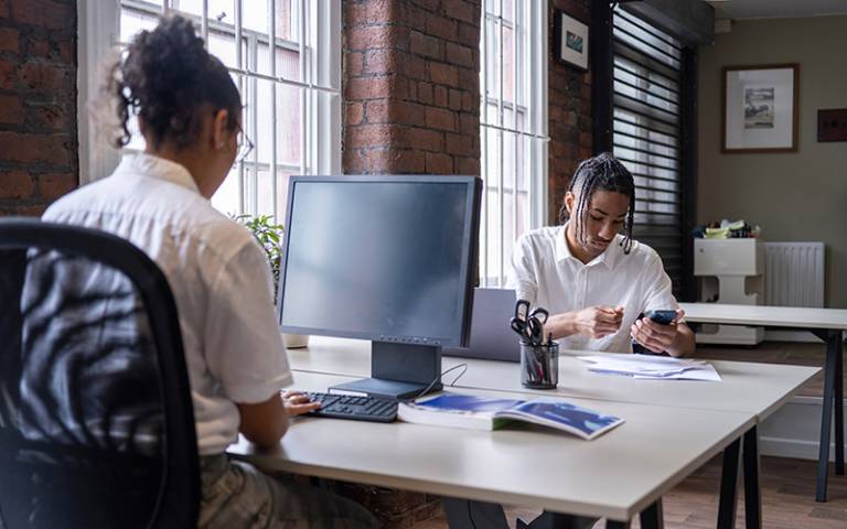 Two young people sitting at desks working in an office (Photo: Cultura Creative / Adobe Stock)