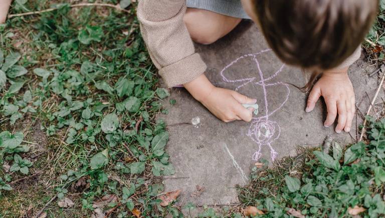 Child drawing a butterfly with chalk outdoors