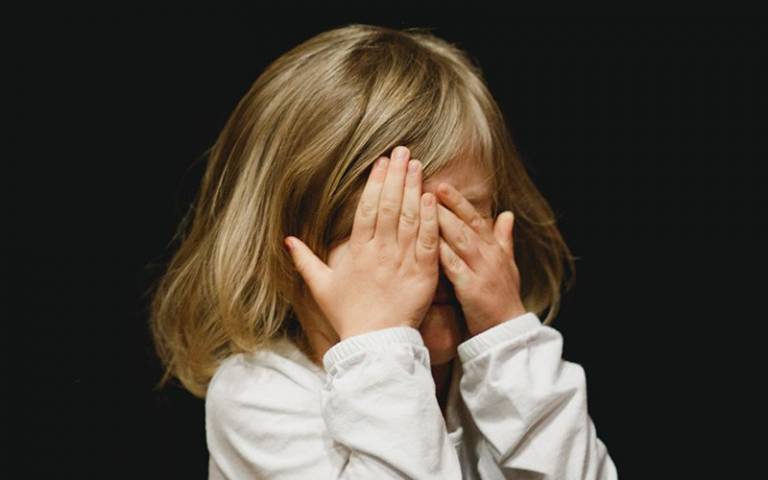 Upset child covering face with hands