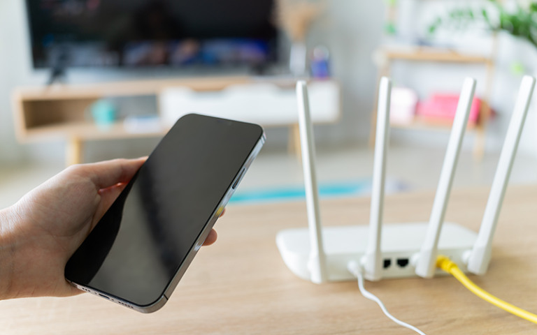 Internet broadband wifi router and mobile phone in a living room. Credit: Timeimage /  Adobe Stock.